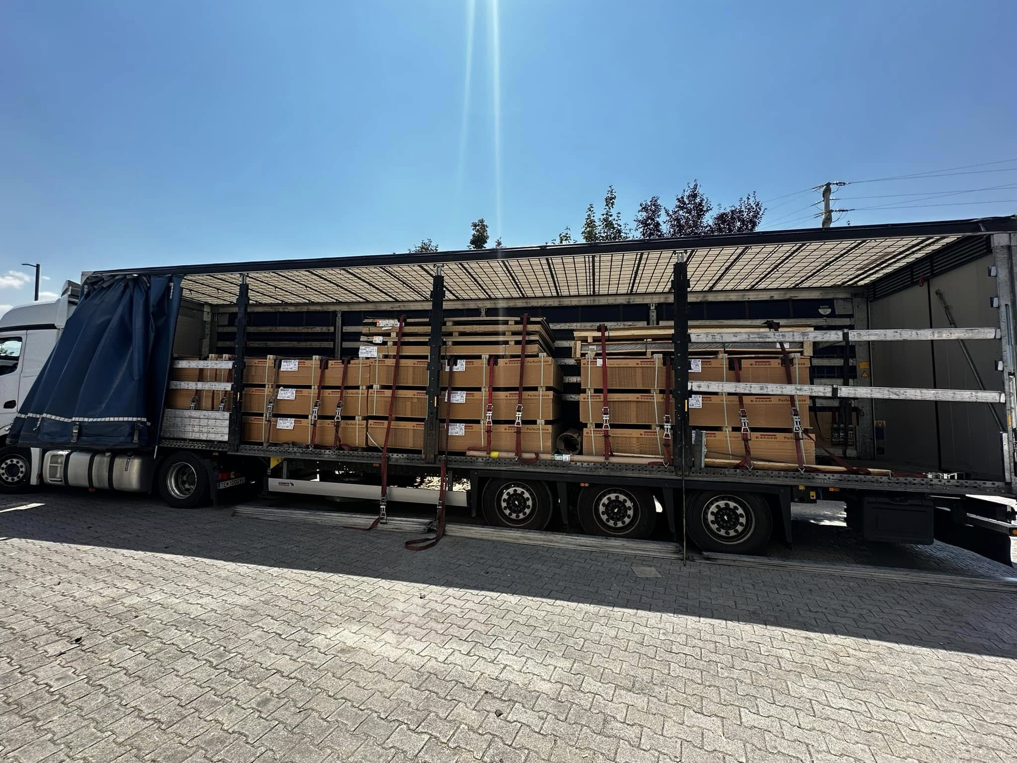 Open-sided trailer with cargo secured by straps