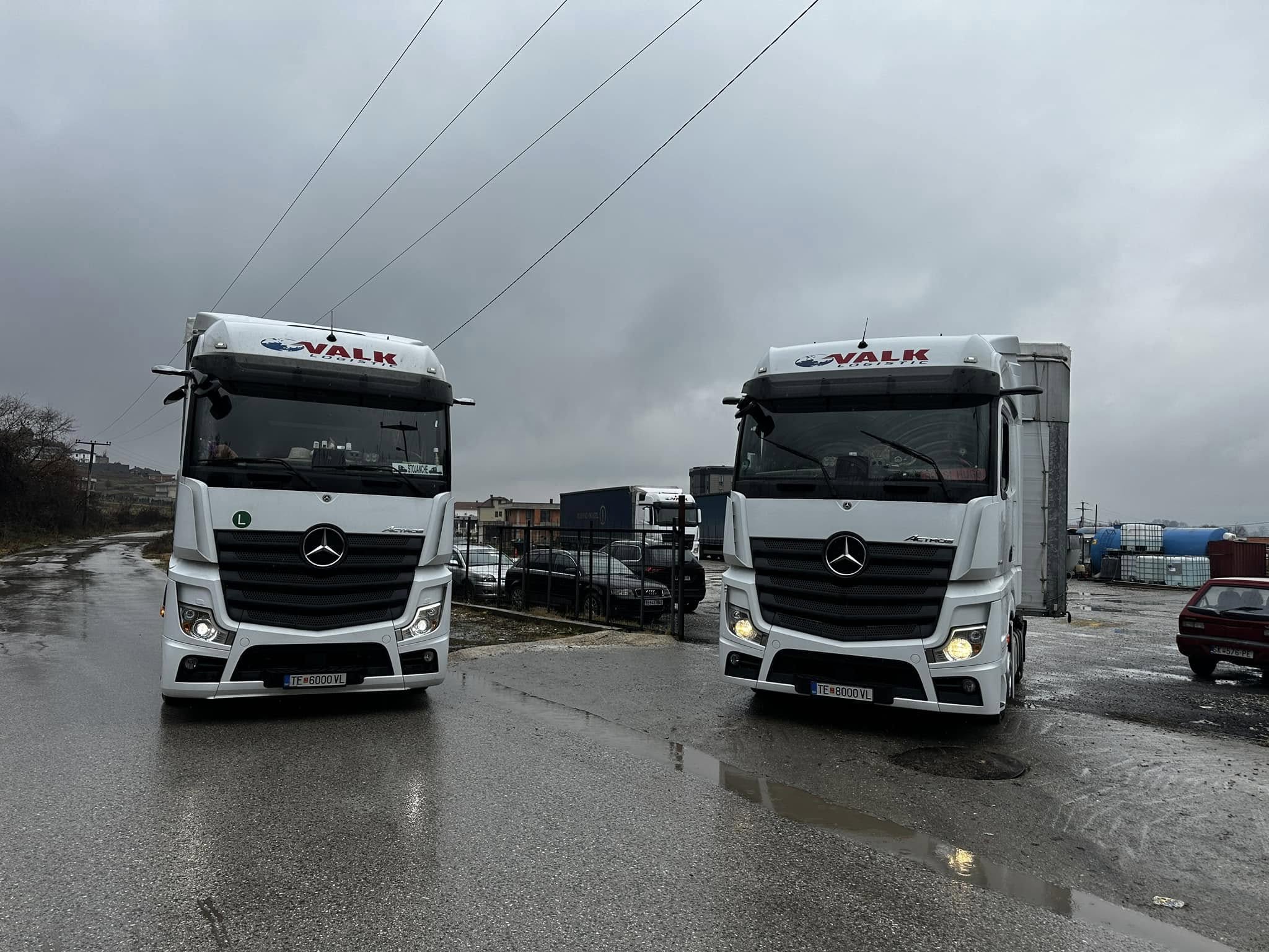 Two white VALK Logistic trucks parked side by side